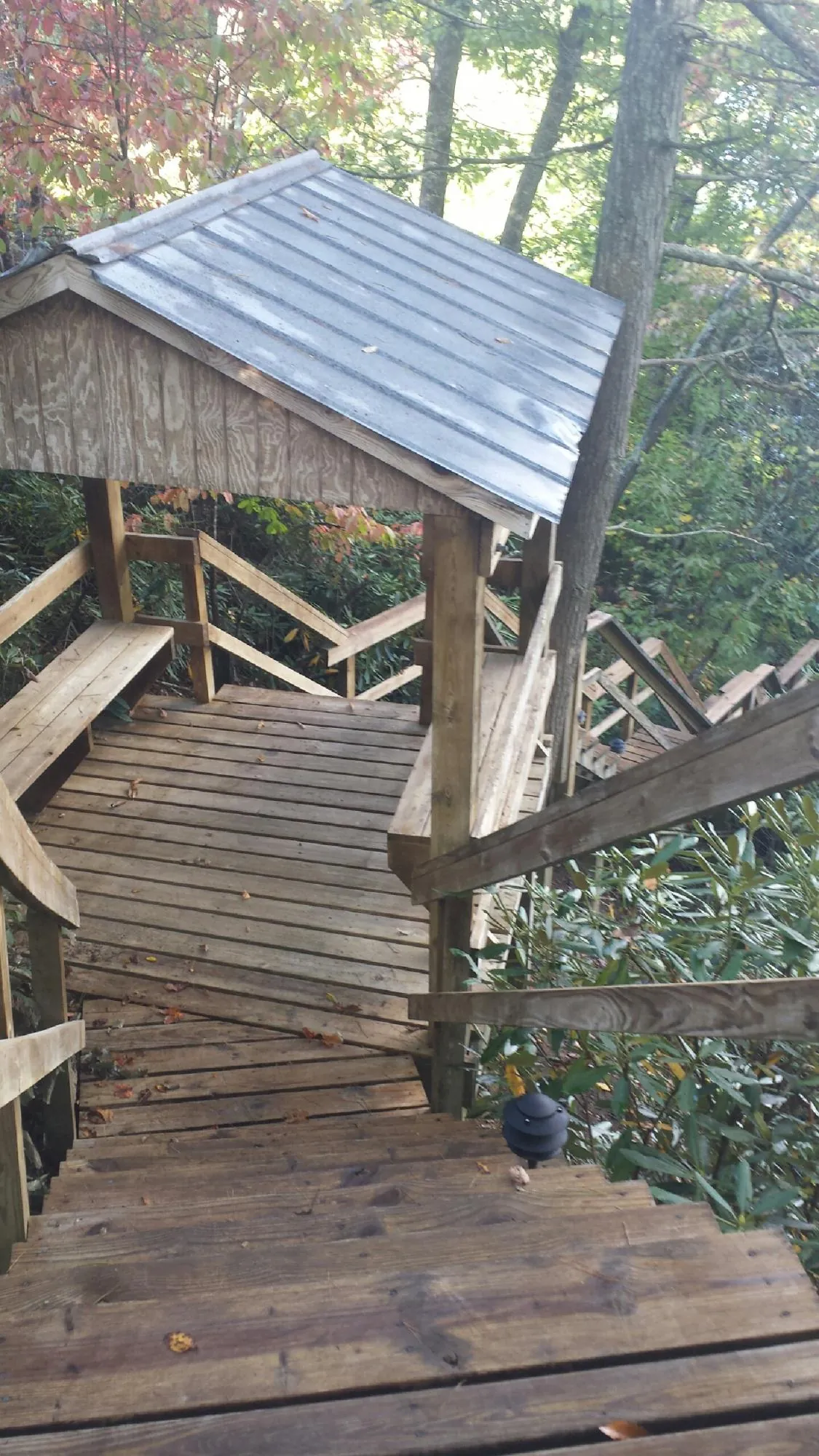 Metal roofed shelter over wooden steps on a wooded walkway — Skylight Repair & Installation work by our crew in Broadway