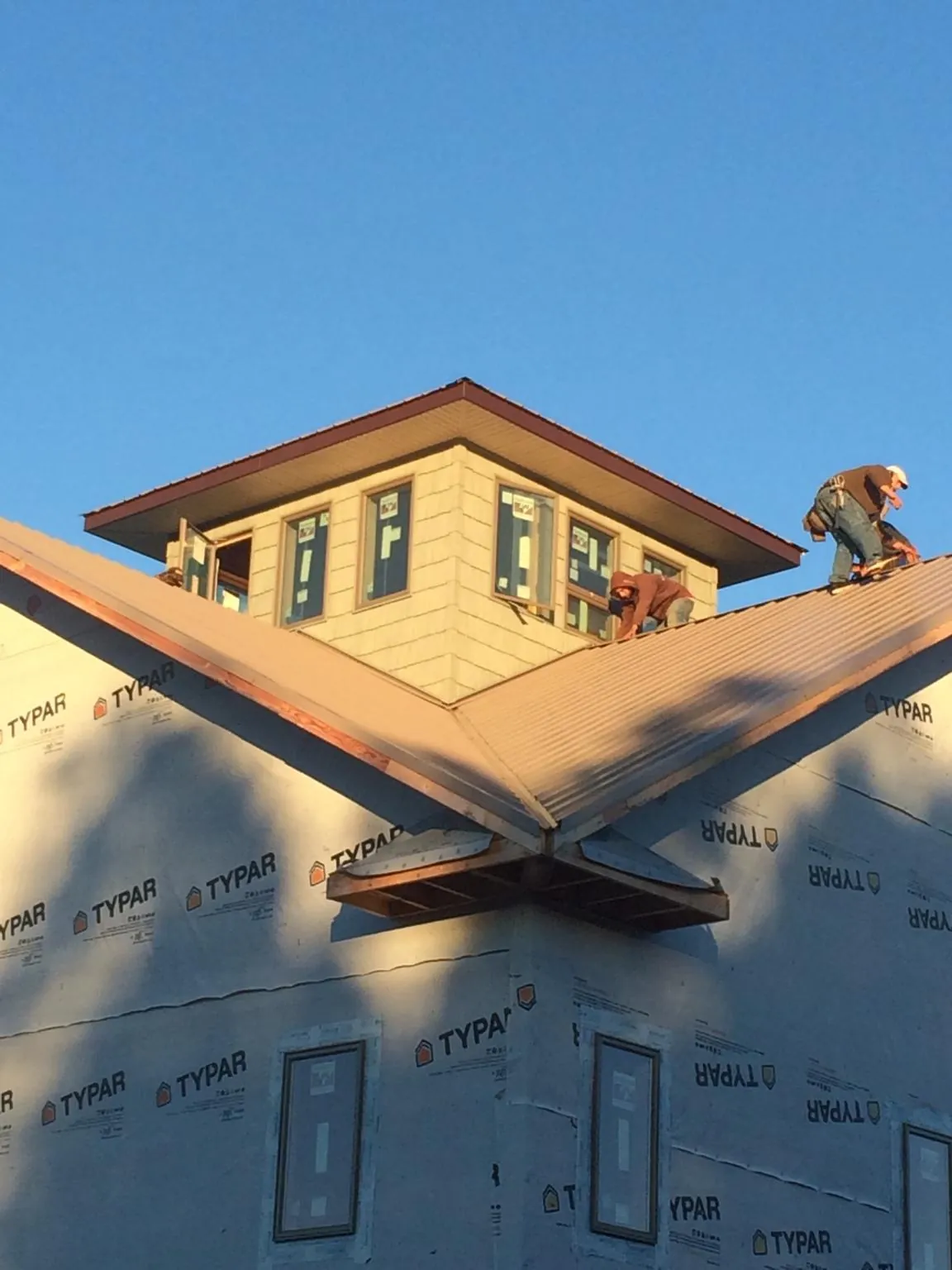 Roofers working around a rooftop cupola on a new metal roof at sunset — Roof Waterproofing in Broadway by Roofing Brothers